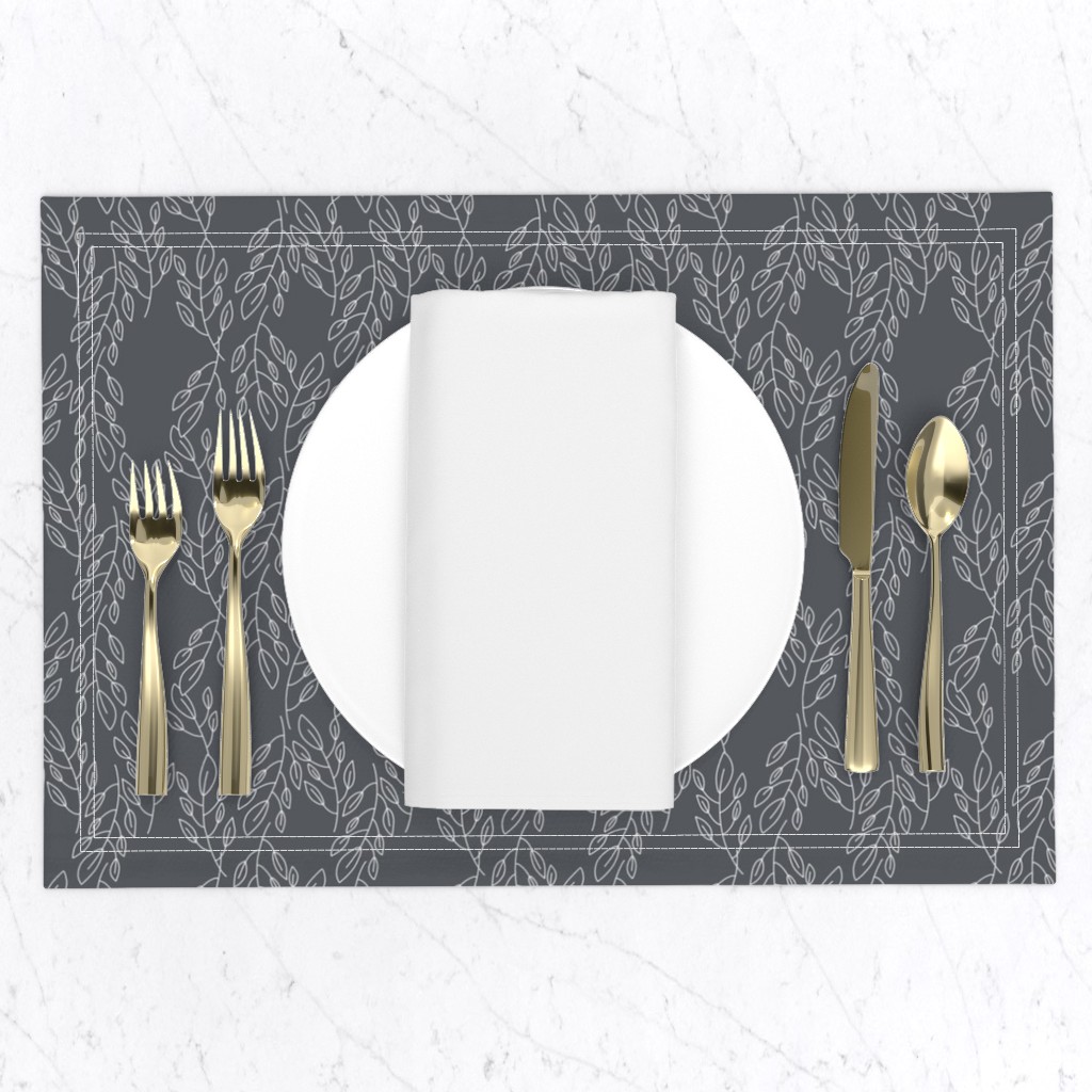 Top down of a table setting on a white marble table, a placemat with a plate and napkin and gold silverware set