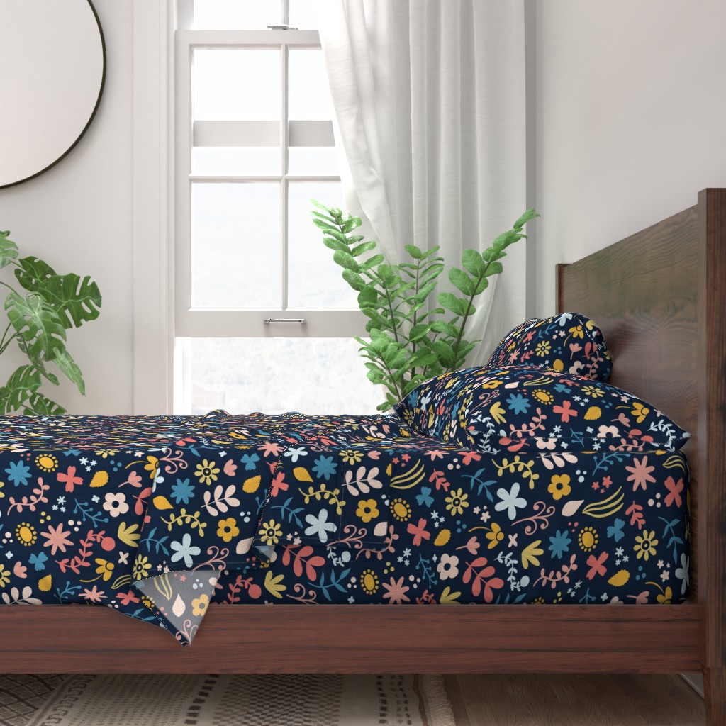 A neatly made bed with sheets and pillows with a wooden bedframe. The bed is next to a window with plants on either side and a round mirror hangs on the wall to the left of the window.