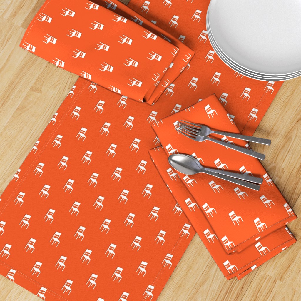 Top down table with a Table Runner placed diagonally with a set of Dinner Napkins, plates and silverware on top