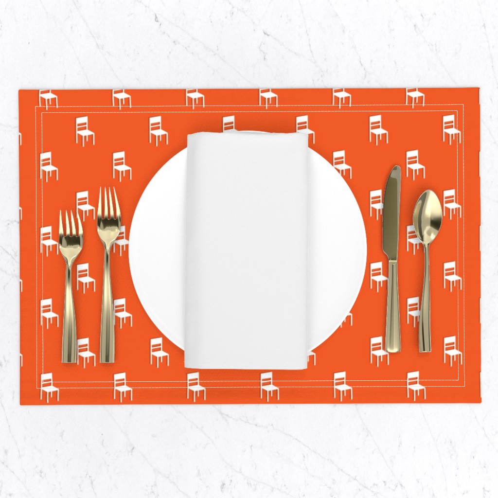 Top down of a table setting on a white marble table, a placemat with a plate and napkin and gold silverware set