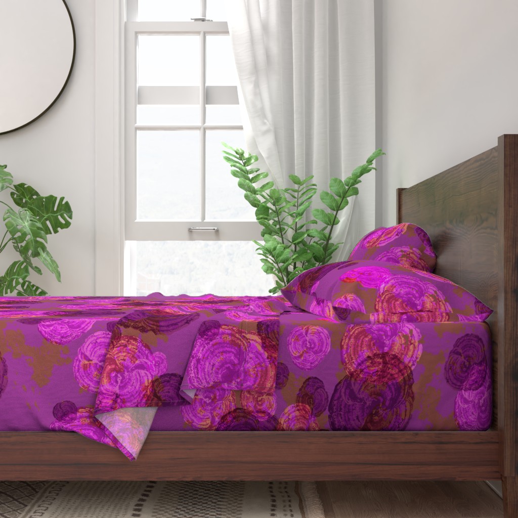 A neatly made bed with sheets and pillows with a wooden bedframe. The bed is next to a window with plants on either side and a round mirror hangs on the wall to the left of the window.