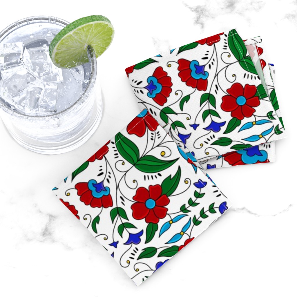 Top down of two folded Cocktail Napkins overlapping next to a glass tumbler full of ice and liquid with a lime wedge on a white marble tabletop