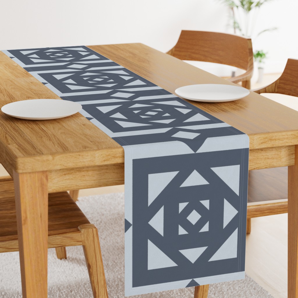 Angled light wood table with a 108 inch long Table Runner in the middle and two plates