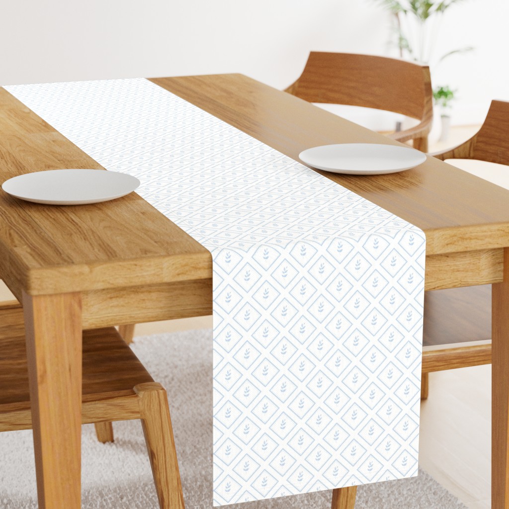Angled light wood table with a 108 inch long Table Runner in the middle and two plates