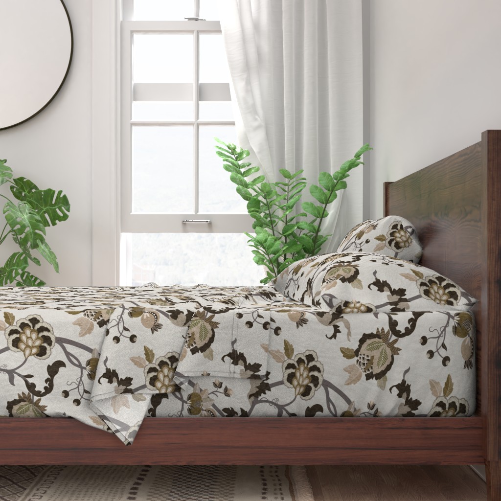 A neatly made bed with sheets and pillows with a wooden bedframe. The bed is next to a window with plants on either side and a round mirror hangs on the wall to the left of the window.