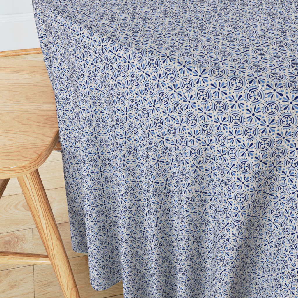 Angeled side view of a round table with wooden chair in the foreground and a 90 inch Tablecloth draped over the edge showing the sewn hem around the edge