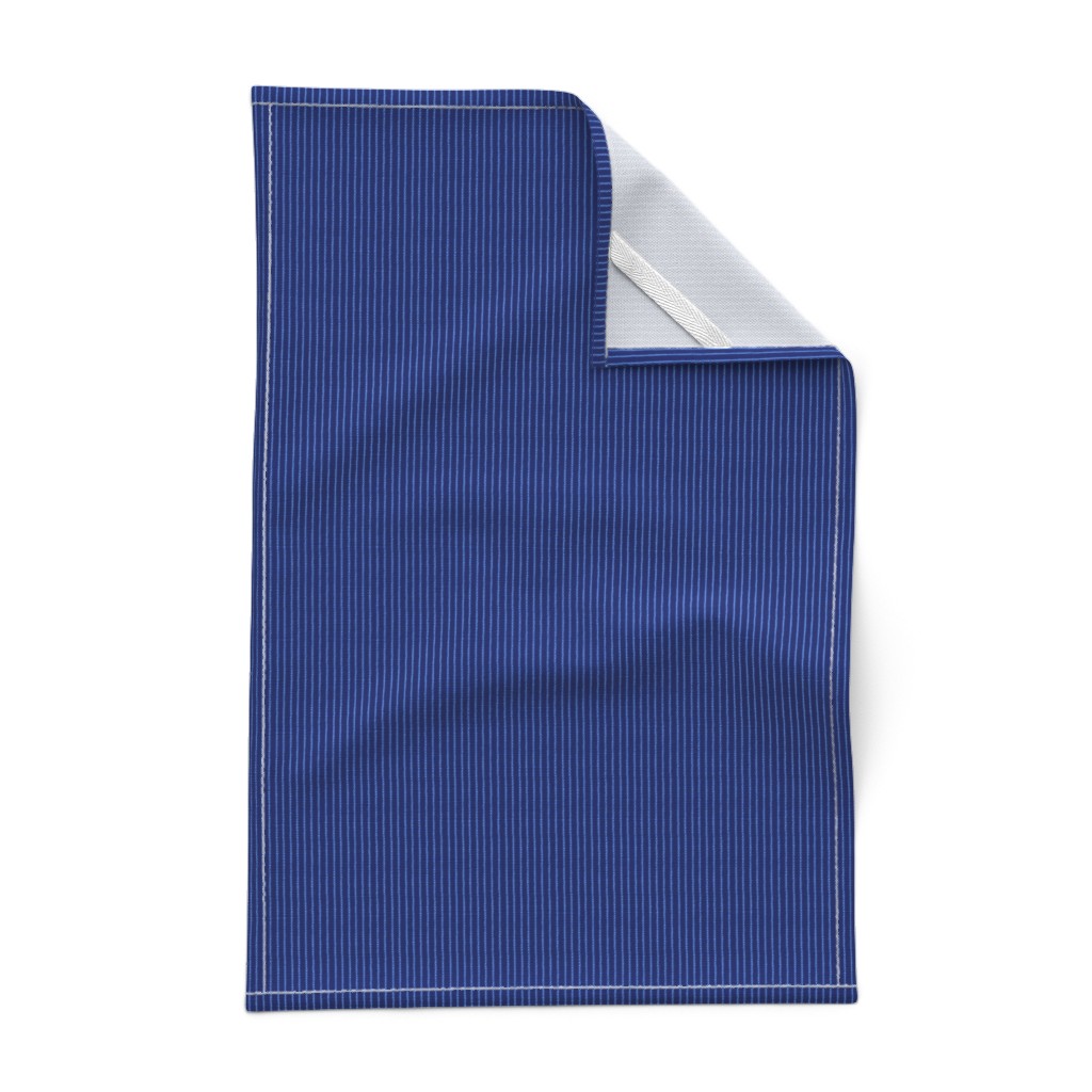 A Tea Towel laying out flat on a white background with the top right corner folded over showing the hem and unprinted backing with the white hanging tab