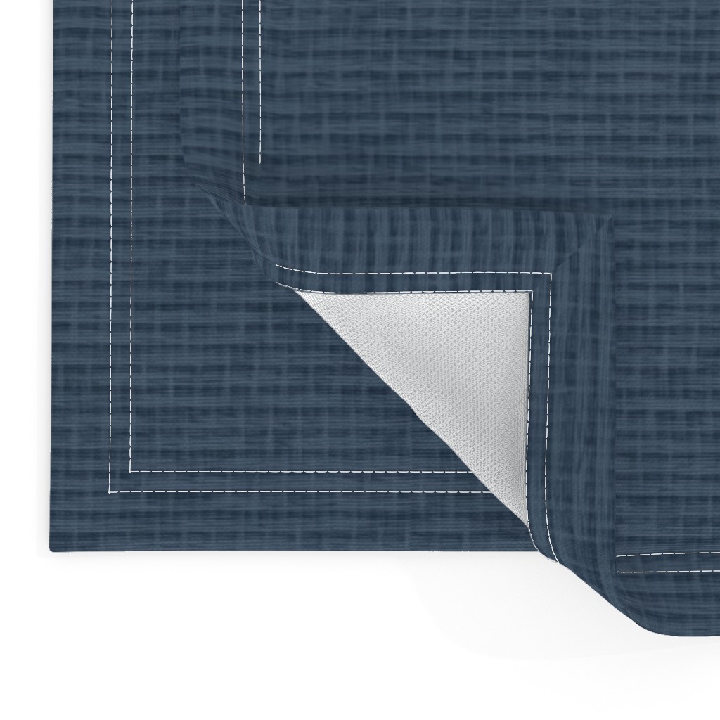 Close up of two Placemats stacked on top of eachother and the top left bottom corner is flipped up showing the hem and unprinted back