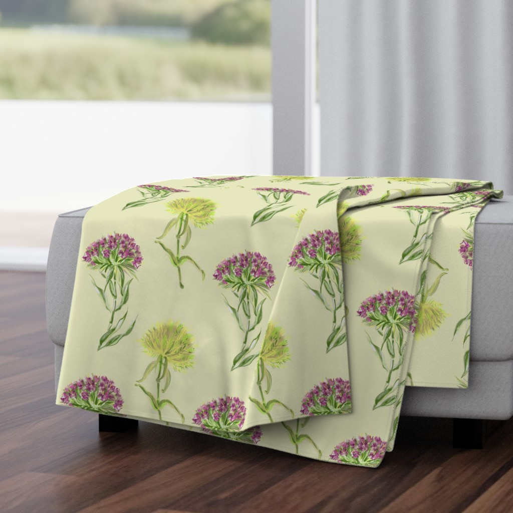 Folded Throw Blanket draped over a plush fabric ottoman in a living room in front of an open window with dark wood floors.