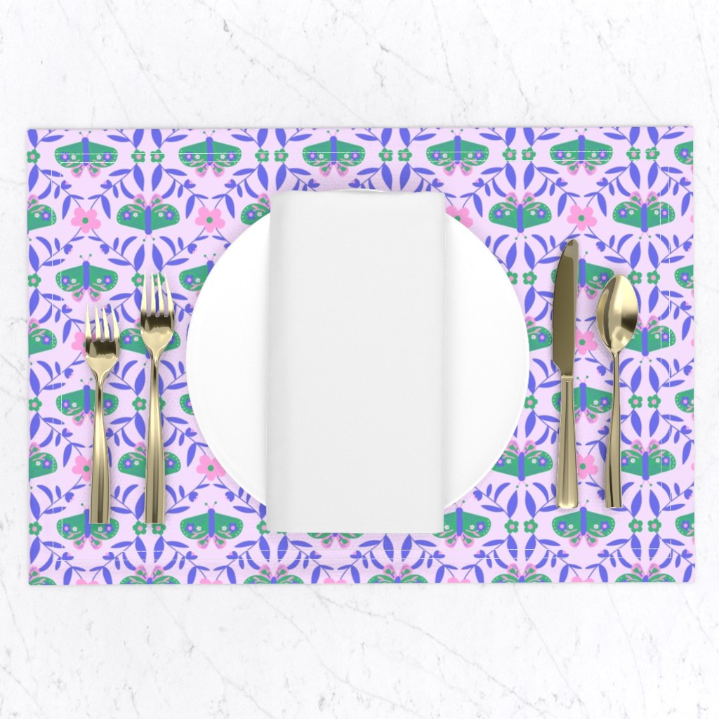 Top down of a table setting on a white marble table, a placemat with a plate and napkin and gold silverware set
