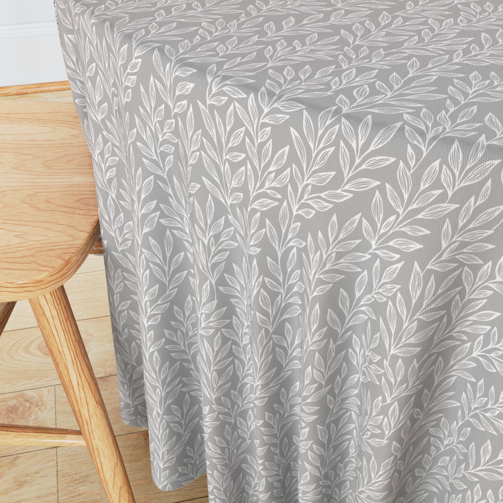 Angeled side view of a round table with wooden chair in the foreground and a 90 inch Tablecloth draped over the edge showing the sewn hem around the edge